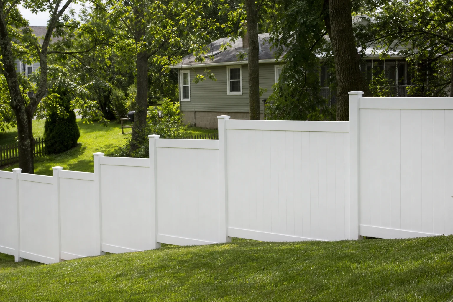 White vinyl privacy fence following a sloped backyard